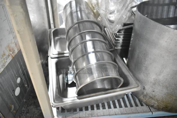 Tiered lot with a metal stock pot and stainless steel cylindrical drop-in bins. Items in used condition, ideal for kitchen use.