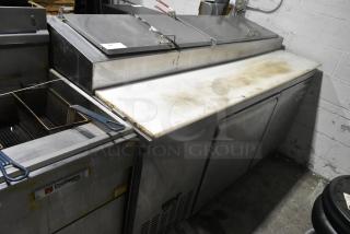 Avantco 178PICL2 stainless steel commercial pizza prep table, 115 volts, features storage compartments and cutting board. Signs of use visible.
