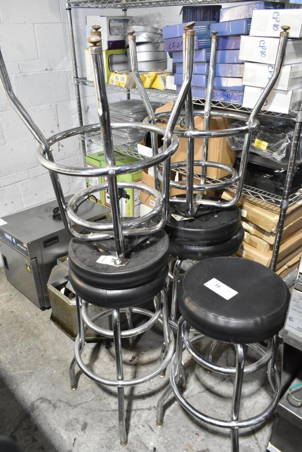 Set of 5 chrome finish bar height stools with black cushions. Appears in good condition. Auction tag visible on cushion.