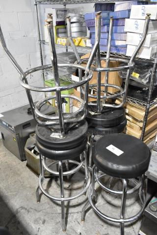 Set of 5 chrome finish bar height stools with black cushions. Appears in good condition. Auction tag visible on cushion.