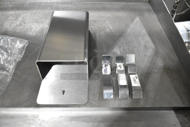 Stainless steel bin with a matte finish, featuring a keyhole on the front. Includes four metal clips with brand tags visible.