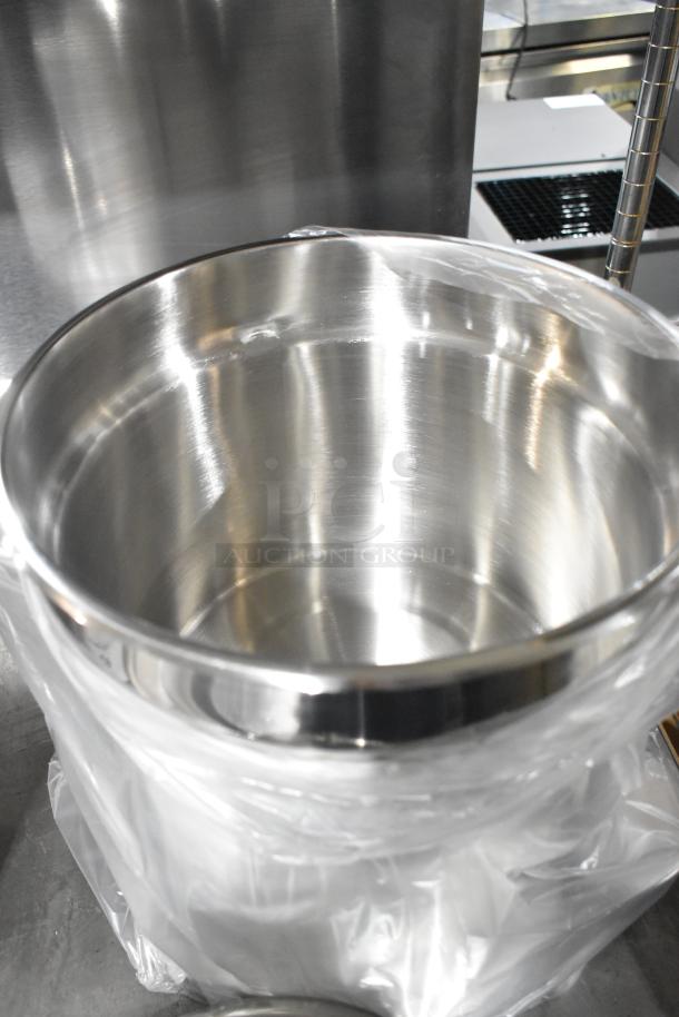 Brand new stainless steel cylindrical drop-in bin, with protective plastic wrapping, shiny finish, auction item.