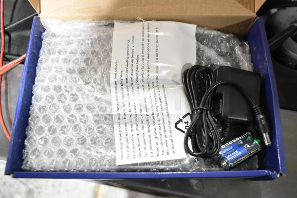 Box containing 9 brand new Update DPS-20 digital portion scales, wrapped in bubble wrap. Includes power adapter and general-purpose batteries.