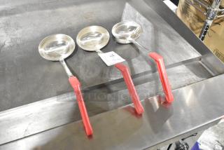 Three metal ladles with red handles, stainless steel finish, excellent condition, auction tag visible.