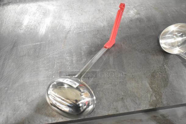 Metal ladle with red handle and visible barcode on the bowl. Stainless steel, reflecting light, in good condition.