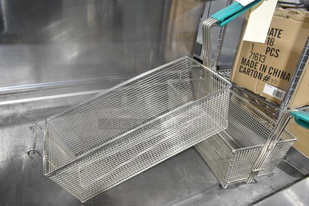 Brand new metal fry baskets with slight scratches and dents, featuring mesh design and green handles.