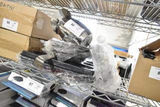 Multiple brand new kitchen items, including a pitcher, ladle, and pan, on a shelf. Items are stacked and wrapped, labeled for auction.