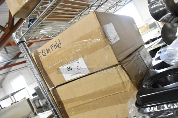 Two new TD-MFOLD paper towel dispensers in boxes labeled and marked for multifold towels, on a metal shelf.