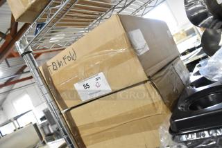 Two new TD-MFOLD paper towel dispensers in boxes labeled and marked for multifold towels, on a metal shelf.