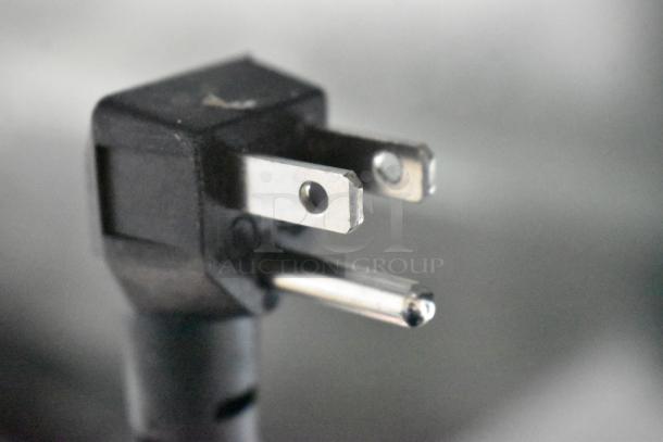 Close-up of a three-prong electrical plug for the Imbera EVC04 mini cooler, highlighting its 115-volt compatibility.
