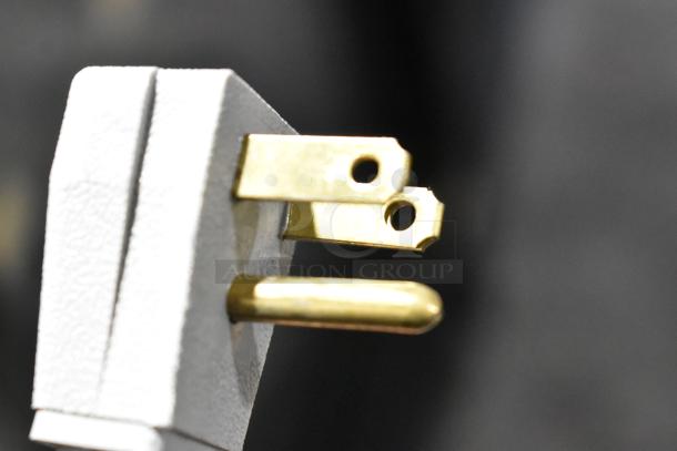 Close-up of a three-prong electrical plug, likely for a True GDM-41SL-48-HC-LD commercial cooler, showing gold-colored prongs.