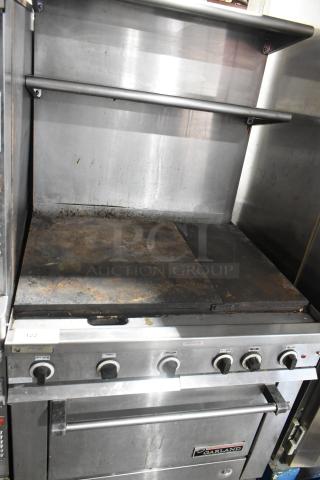 Garland stainless steel commercial gas griddle with oven, overshelf, and backsplash. Used condition, visible wear.