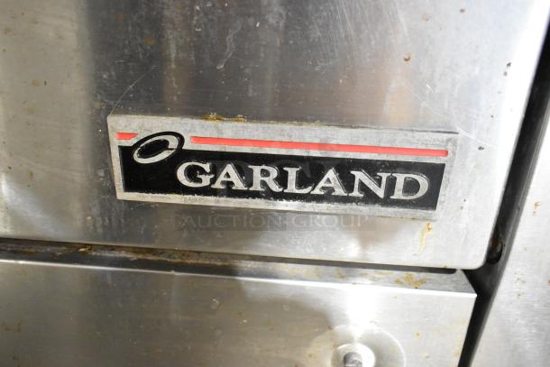 Garland stainless steel commercial gas flat top griddle with oven, over shelf, and backsplash. Features visible logo.