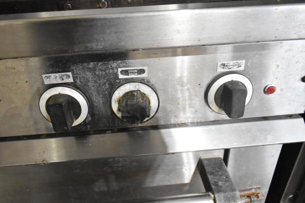 Garland stainless steel commercial gas flat top griddle with oven. Features control knobs labeled "oven" and "bottom." Signs of use.