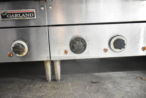 Garland stainless steel countertop electric griddle, three control knobs, visible wear, ideal for commercial use.