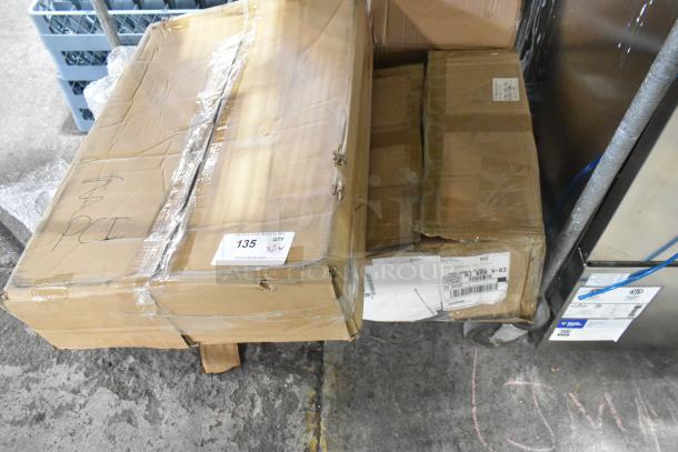 12 new scratch and dent items in boxes, including Bakers Lane baking pans, stainless steel bin lids. Boxes show shipping labels.