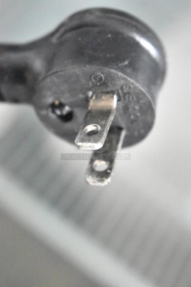 Close-up of a power plug for 2021 True GDM-12-HC commercial cooler, showcasing metal prongs and durable black casing.