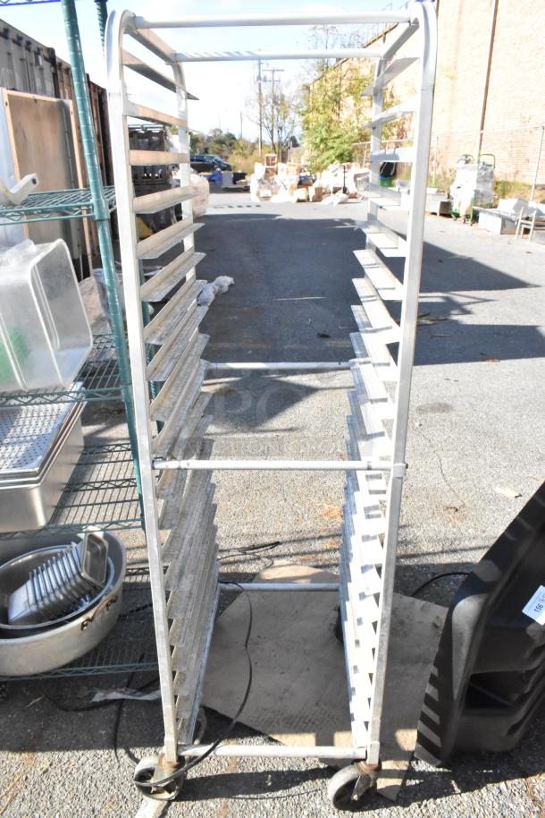 Metal commercial pan transport rack on wheels, featuring multiple slots for pans. Used condition, sturdy design, commercial casters.