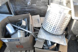 Pallet lot with metal stock pot, stainless drop-in bins, baking pan, whisk, and metal scoop; used condition in boxes.