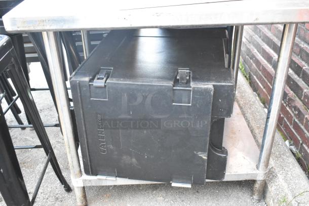 Stainless steel table with metal under-shelf, Carlisle black poly insulated food carrier, and metal bowls. Auction lot.