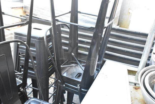 5 black metal Tolix style bar stools, stackable, showing light wear, suitable for indoor or outdoor use.