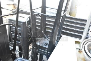 5 black metal Tolix style bar stools, stackable, showing light wear, suitable for indoor or outdoor use.