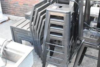 4 black metal Tolix style bar stools in used condition, stackable, minimal surface wear.