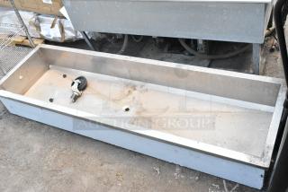 Metal drop-in sink with drain hole, slight surface wear, industrial setting, measuring approximately 5 feet in length.