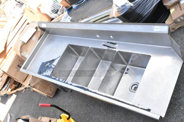 Stainless steel 3 bay sink with left side dirty dish table, signs of wear, suitable for commercial kitchens.