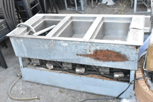 Stainless Steel Commercial 3 Bay Drop In Steam Table, used condition, visible rust and wear on exterior, with hoses attached.