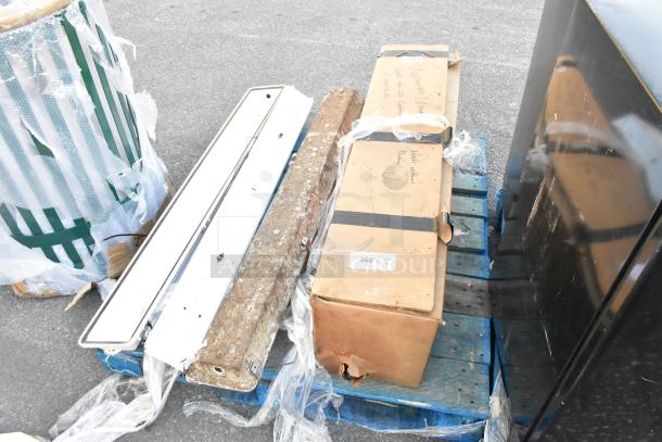 Four assorted items on a pallet, including a wrapped Unicarriers forklift cylinder, various boards, and a box marked "used."