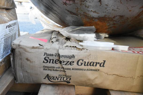 Damaged box labeled "Pass-Through Sneeze Guard" compatible with Avantco Hot Dog Roller Grills, on wooden pallet.