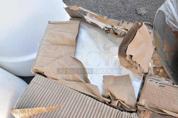 Damaged cardboard box showcasing scratch and dent items including wine glasses, paper towel dispenser, and pouches.