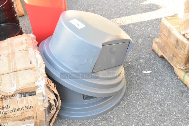 Two sturdy gray poly trash can lids with side openings, stacked together. Visible label shows auction reference number.