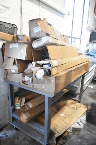 Table with 12 brand new items in boxes, including GM22936585 Cargo Area Security Enclosure, GM23256564 Roof Luggage Rail.