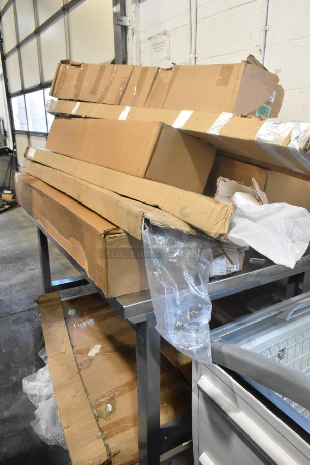 Table with 12 brand new items in boxes, including GM cargo area security enclosure, roof luggage rail, and grille.