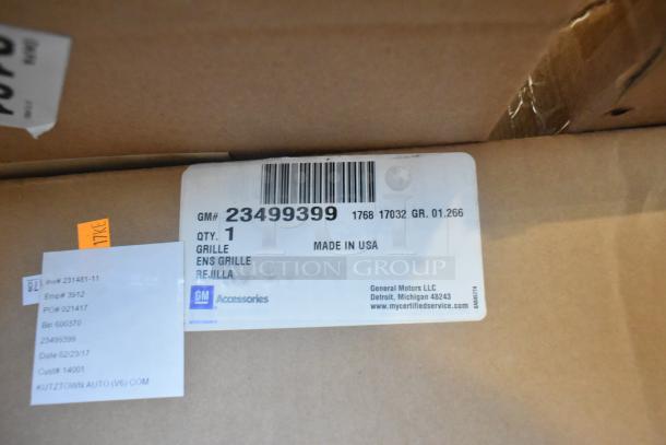 Table lot of 12 brand new GM items, including GM 23499399 Grille. Tags show item details and origin as Made in USA.