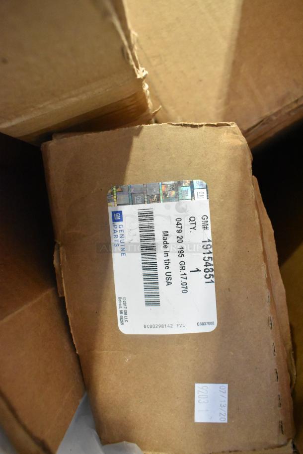 Table lot of 12 brand new GM items, includes GM22936585 cargo enclosure, GM23256564 roof luggage rail, visible label indicates GM part 19154851, made in the USA.