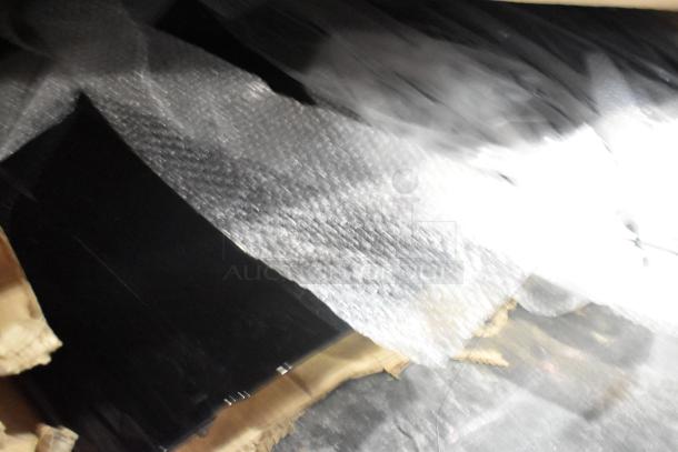 Table lot of 12 brand new items wrapped in bubble wrap, including GM cargo area security enclosure, roof luggage rail, grille, and roof rail.