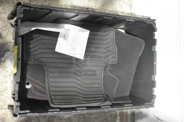 Black poly bin containing various brand new car mats, black with red stitching. Barcode label visible on document.