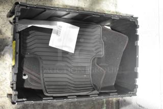 Black poly bin containing various brand new car mats, black with red stitching. Barcode label visible on document.