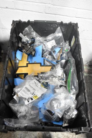 Brand new lot of various car parts in a black poly bin, featuring Chevy emblems in sealed plastic bags, with labels and markings visible.