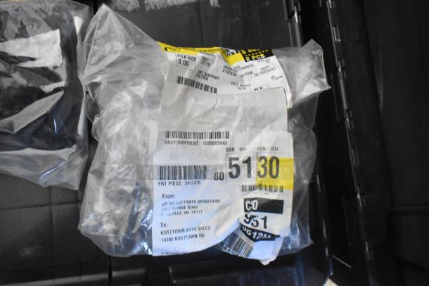Black poly bin with brand new car parts, including Chevy emblems, features labeled packaging with shipping details.