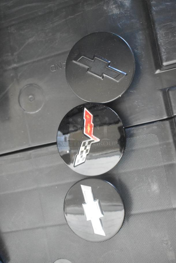 Brand new Chevy emblems in black poly bin; includes chrome and checkered designs, pristine condition.