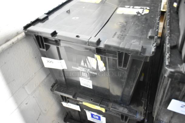 Black poly bin containing various brand new car parts, including a brake light and Cadillac valve stem caps. Labels indicate GM ownership.