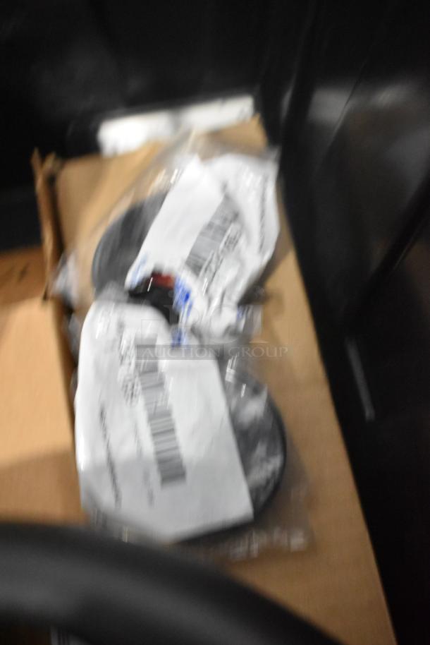 Blurred image of various car parts including a brake light and Cadillac valve stem caps in a black poly bin, brand new condition.