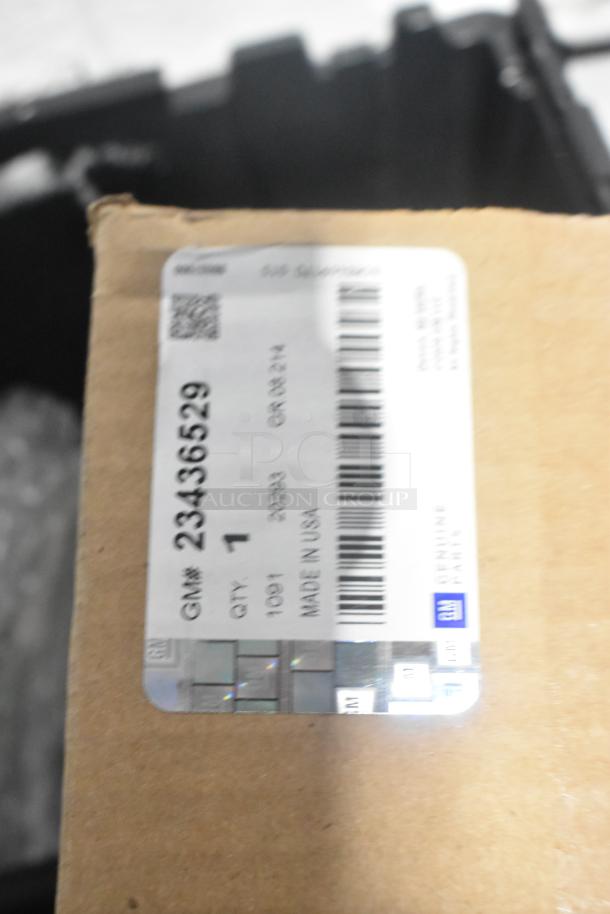 Lot of new car parts including brake light, Cadillac valve stem caps in black poly bin. Label shows GM part 23436529, made in USA.