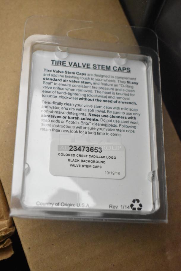 Brand new Cadillac valve stem caps, colored crest logo, black background, in packaging. Origin: U.S.A, Part No: 23473653.