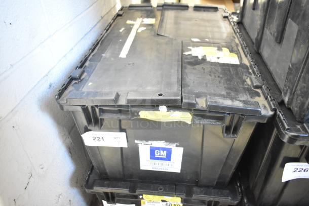 Black poly bin containing a variety of brand-new car parts, including car mats. Marked with GM label and auction tag number 221.