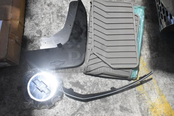 Brand new car parts including black car mats in poly bin, Chevrolet logo visible, label reads "RH Rear Made in USA".